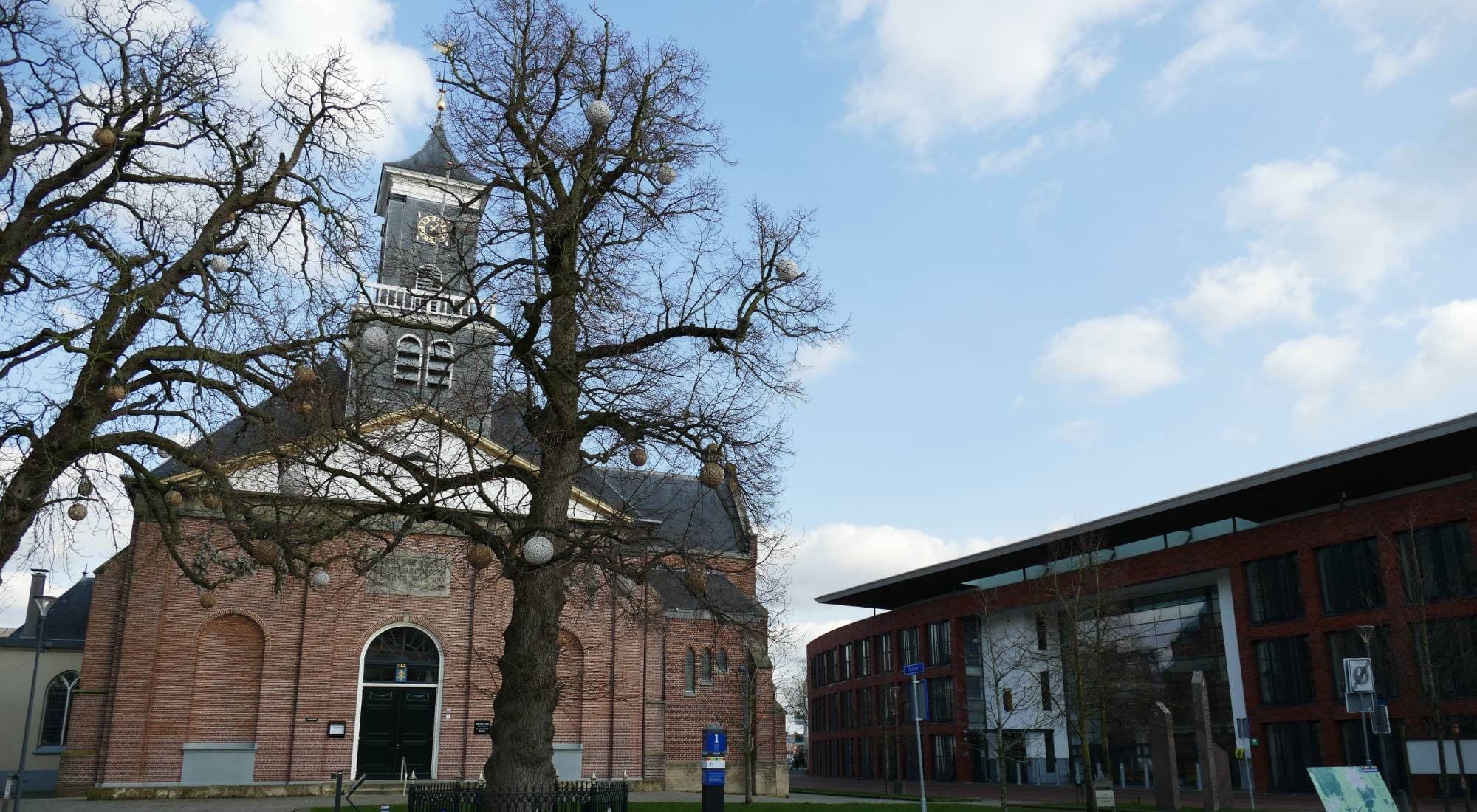 De Schildkerk in Rijssen met de Koningin Wilhelminaboom ervoor en rechts het gemeentehuis